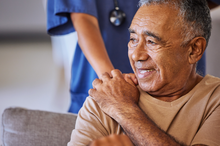 Older adult receiving support from a healthcare professional, with the provider's hand resting on the patient's shoulder, symbolizing compassionate care, recovery, and patient support.