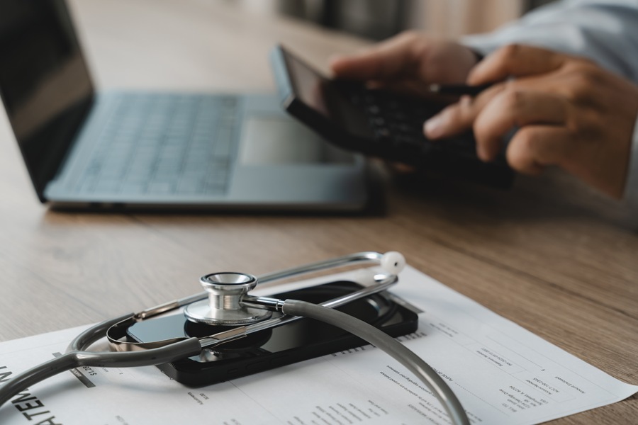 Person using a calculator to review medical bills and healthcare expenses.