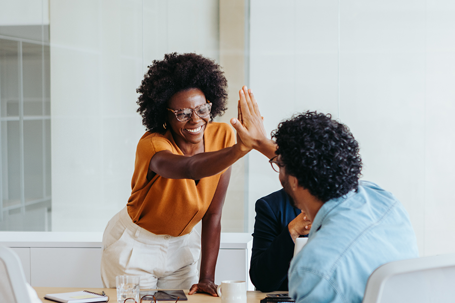 Coworkers sharing a high five in an office, representing teamwork and workplace success.